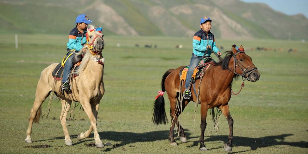 Gémeos no dorso do cavalo na Região Autónoma de Xinjiang