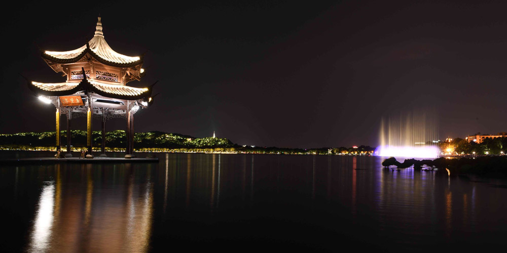Turistas apreciam a vista noturna do Lago do Oeste em Hangzhou