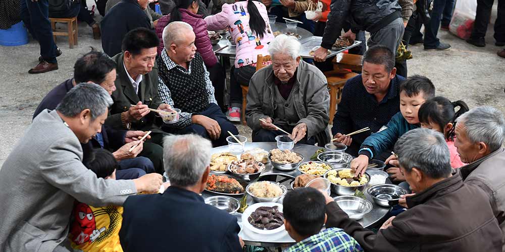 Pessoas do grupo étnico Mulao participam do "Banquete de 100 famílias" durante Festival Yifan