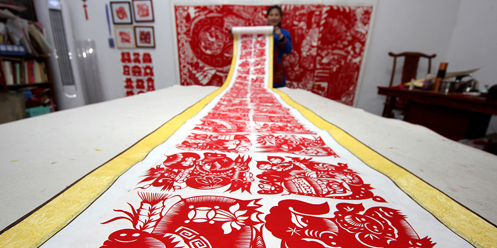 Artista folclórica faz trabalho de corte de papel com tema de porco em Shandong