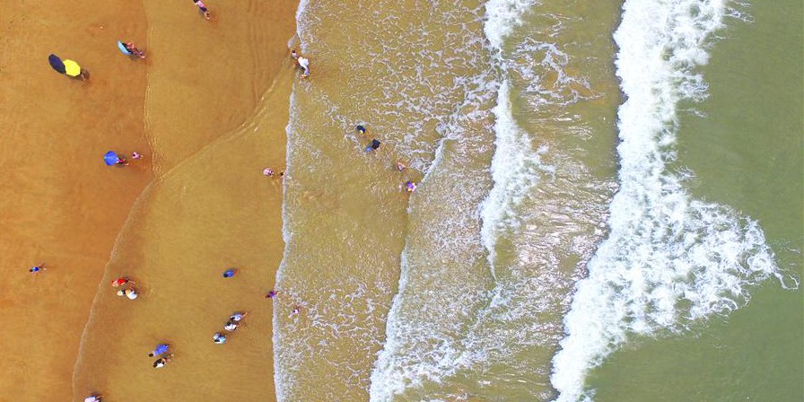 Visitantes se divertem em praia de Qingdao, leste da China