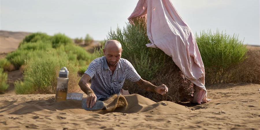 Turistas experimentam terapia de areia em deserto de Xinjiang
