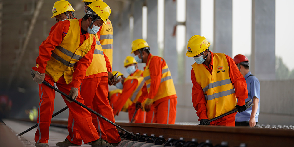 Trabalhadores assentam trilhos para a ferrovia interurbana Beijing-Xiongan
