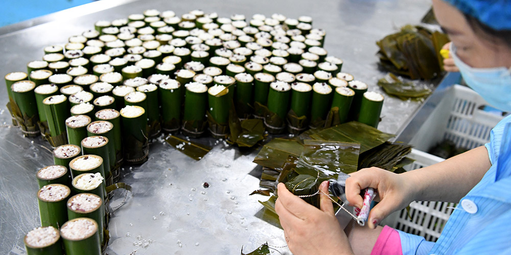 Funcionárias de empresa alimentícia preparam zongzi para celebrar festival anual do Barco do Dragão em Henan