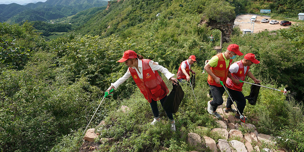 Voluntários limpam lixo ao longo da Grande Muralha de Zhengguanling em Hebei