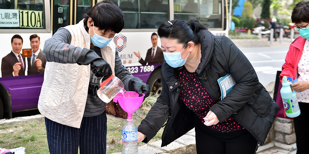 Moradores locais recebem desinfetante distribuído gratuitamente pela Federação dos Sindicatos de Hong Kong